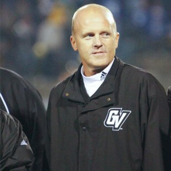 Tim Selgo, dressed in a windbreaker with GV printed on it, smiles beneath stadium lighting.